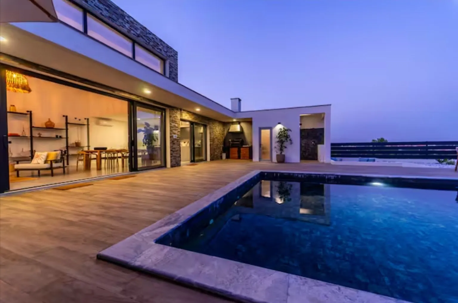 Casa contemporánea al atardecer con piscina y tarima de madera